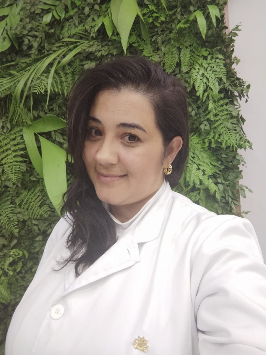 Tatiane Cubos, podóloga e biomédica, de jaleco branco em seu espaço de atendimento